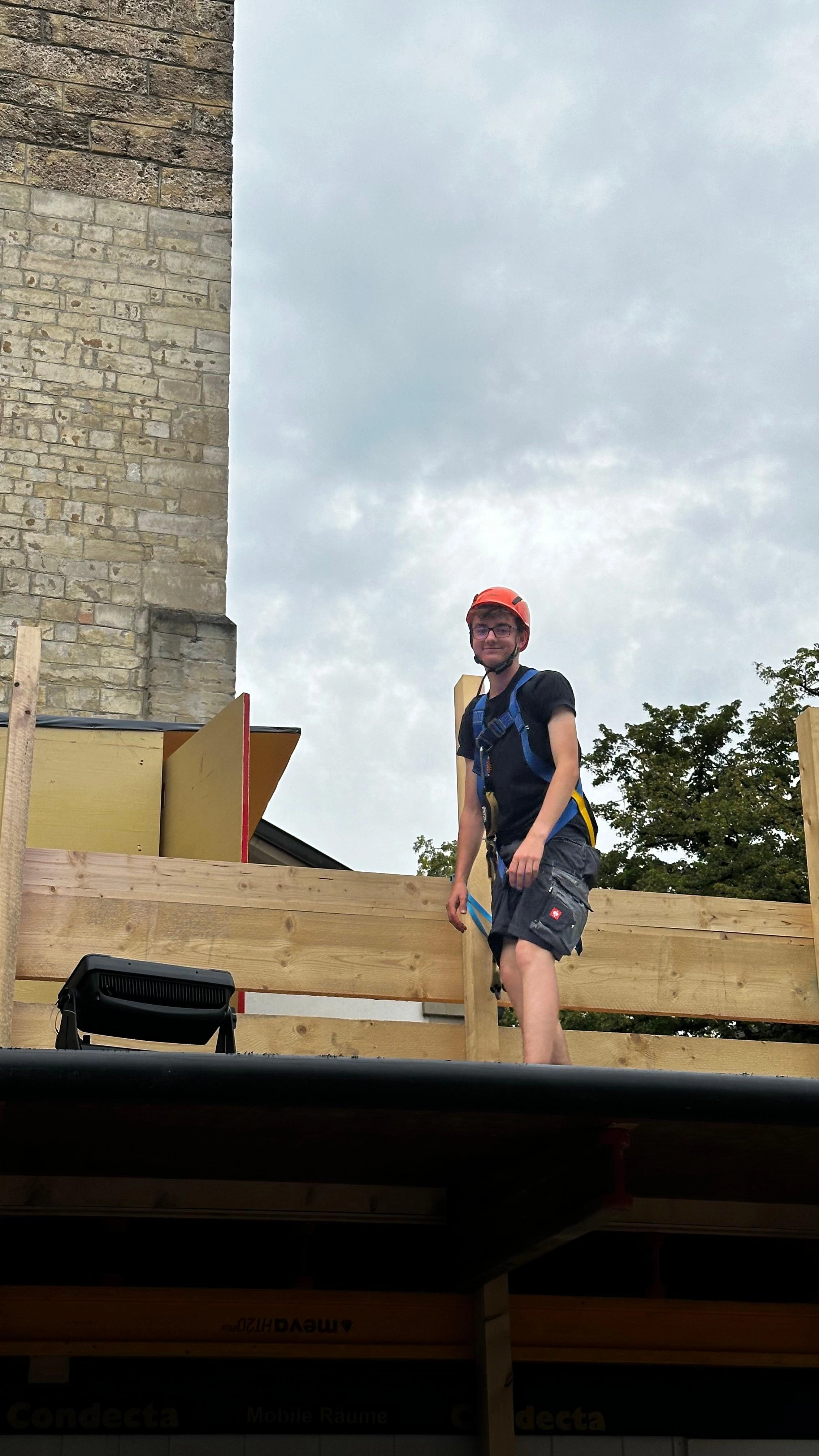 Hier steht Paul mit einer Absturzsicherung auf einem aus Holz gebauten Dach. Das Foto stammt von den Winterthurer Musikfestwochen, wo er jährlich beim aufbauen hilft.