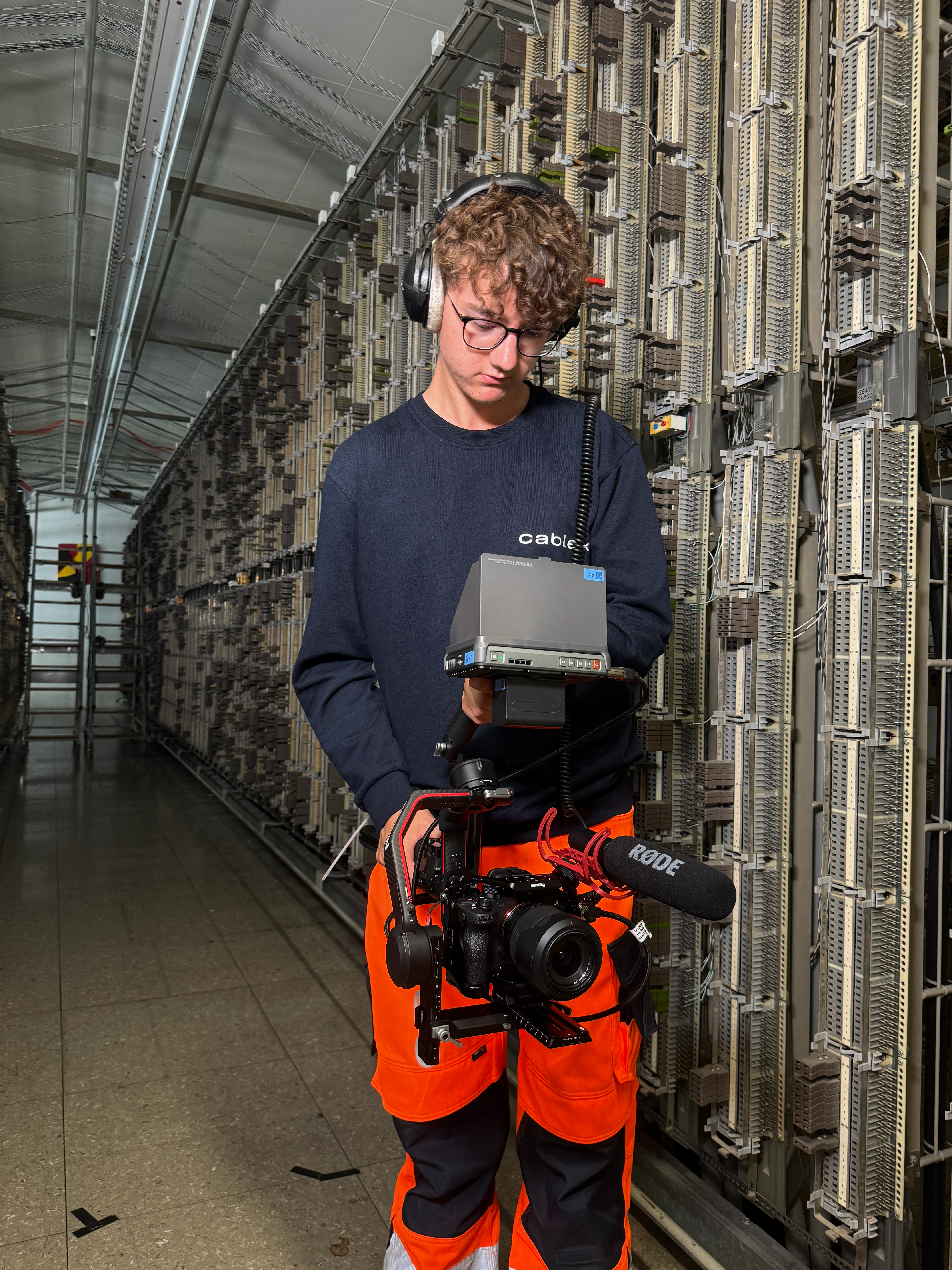 Paul filmt mit einer Kamera und einem Gimbal in einer Telefonzentrale von cablex im Swisscom Gebäude an der Genfergasse in Bern.